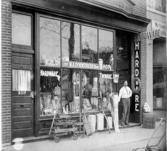 Millard standing at the entrance to his Hardware Store